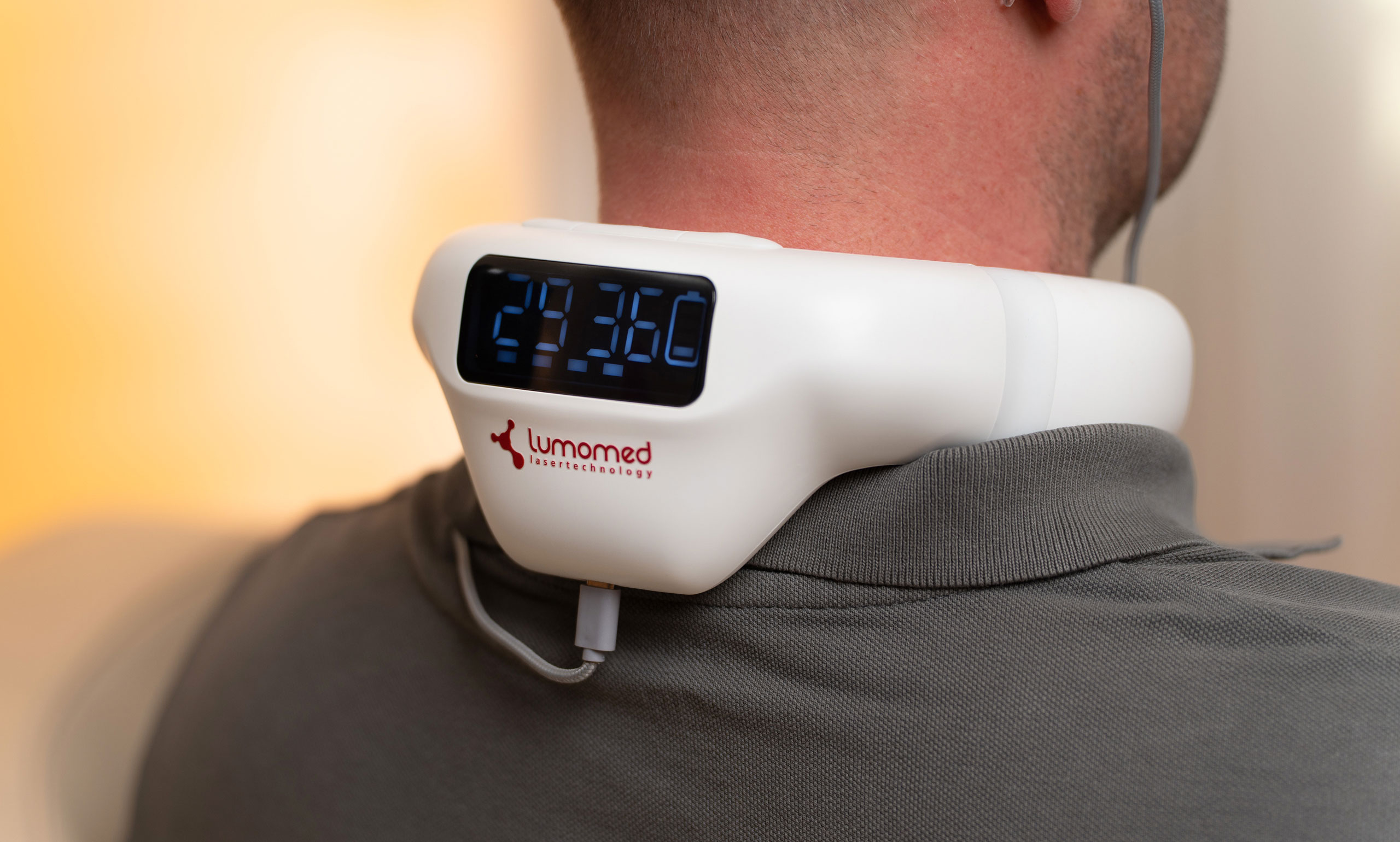 Mann mit LumoHome Lasertherapie am Ohr und Nacken