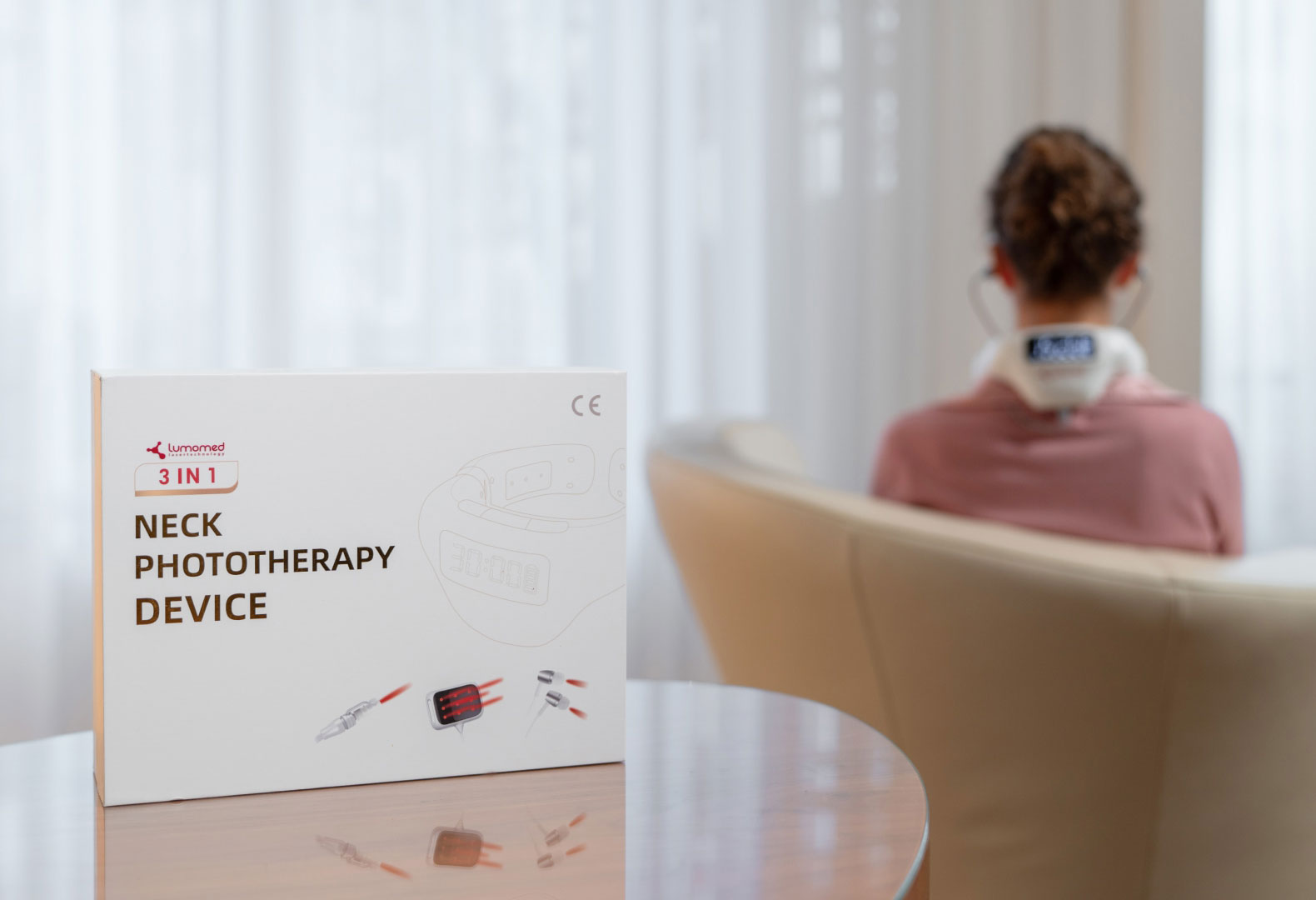 LumoHome Produktverpackung im Vordergrund, im Hintergrund eine Anwenderin mit aktiviertem Lasergerät